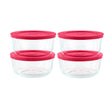 Set of four clear glass food storage containers with pink lids on a white background