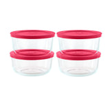 Set of four clear glass food storage containers with pink lids on a white background