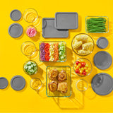 Pyrex glass storage set with gray lids and vibrant food on a yellow background