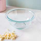 Clear glass bowl with blue rim on a white surface, surrounded by white chocolate chips.