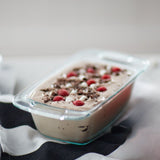 Frozen dessert with raspberries and chocolate shavings in a glass container on a striped fabric background