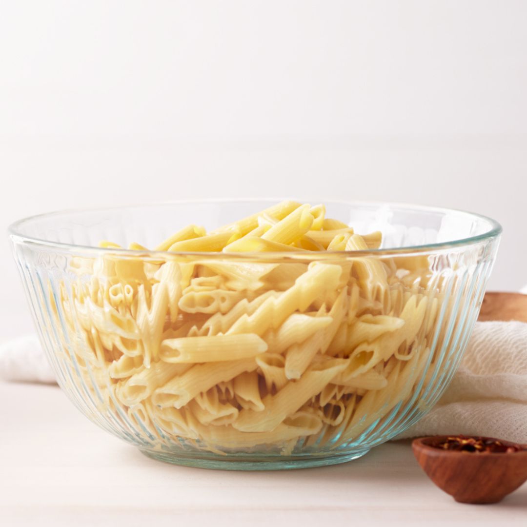 Glass bowl filled with cooked noodles on a white background