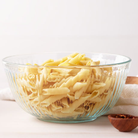 Glass bowl filled with cooked noodles on a white background