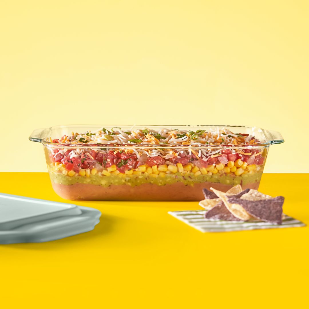 Glass dish with layered salad on a yellow background