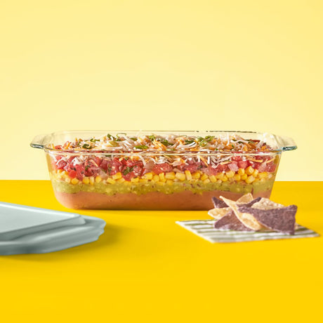 Glass dish with layered salad on a yellow background