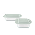 Two glass food storage containers with green lids on a white background