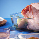 Sliced ham in a glass container with a blue background