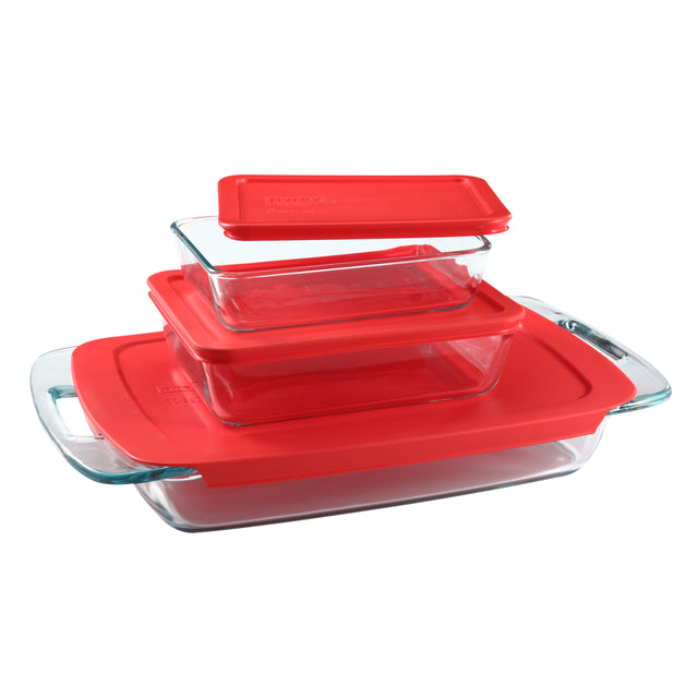 Set of glass baking dishes with red lids on a white background