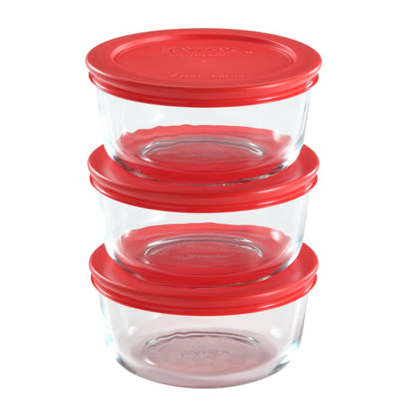 Set of glass food storage containers with red lids on a white background