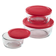 Set of glass food storage containers with red lids on a white background